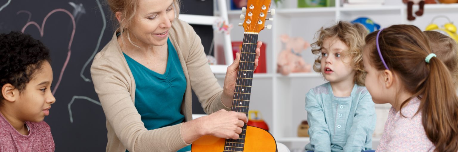 Gitarrenlehrerin unterrichtet Schüler der Grundschule
